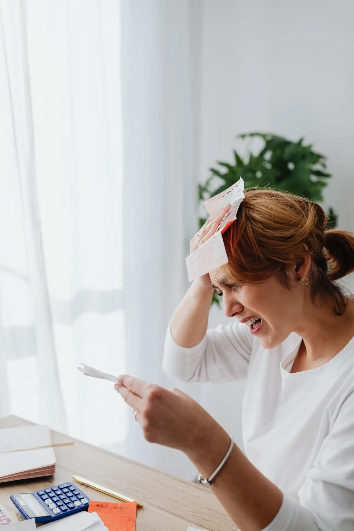 A woman at a desk sorting paper bills, with her face and hands in focus.